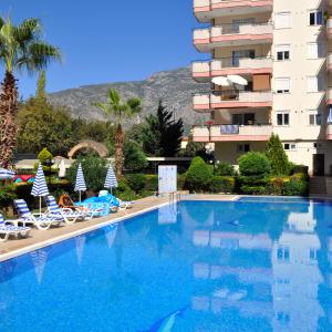 Χαλάρωση δίπλα στην πισίνα σε ένα ηλιόλουστο συγκρότημα διαμερισμάτων στην Αλάνια με θέα στο βουνό.